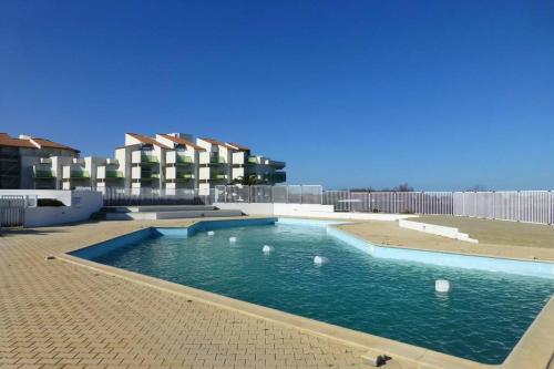 une piscine avec de l'eau bleue devant un immeuble dans l'établissement Les Goelettes - Appartement en RDC avec accès direct à la plage, à Saint-Cyprien