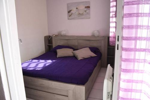 Cette petite chambre comprend un lit avec des draps violets. dans l'établissement Les Goelettes - Appartement en RDC avec accès direct à la plage, à Saint-Cyprien