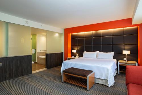 a bedroom with a large bed and a red chair at Holiday Inn Mexico City-Plaza Universidad by IHG in Mexico City