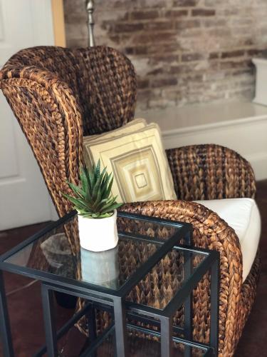 a rattan chair with a glass coffee table and a plant at Suites at 249 in Culpeper