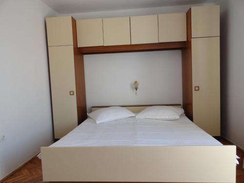 a bedroom with a large white bed with white sheets at Apartments & Rooms Karmela in Banjol