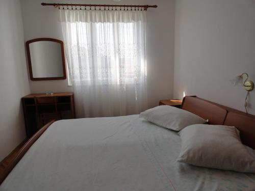 a bedroom with a bed with a mirror and a window at Apartments & Rooms Karmela in Banjol