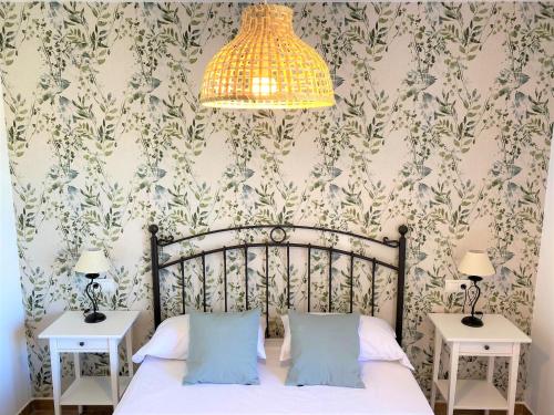 a bedroom with a bed with two tables and a chandelier at Gust De Sal in Denia