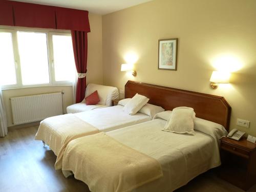 a hotel room with two beds and a telephone at Hotel y Casona El Carmen in Perlora
