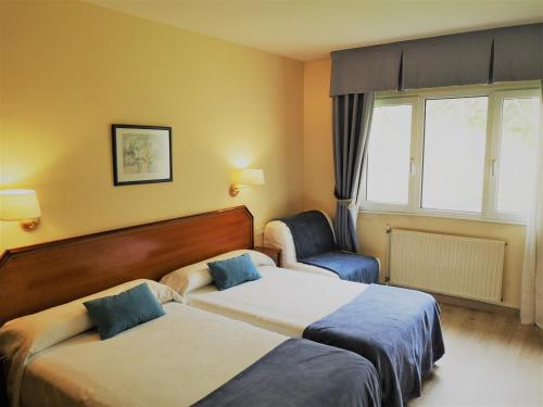 a hotel room with two beds and a chair at Hotel y Casona El Carmen in Perlora