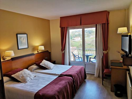 a hotel room with a bed and a balcony at Hotel y Casona El Carmen in Perlora