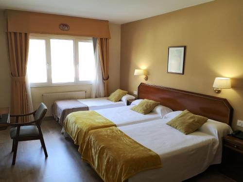 a hotel room with two beds and a chair at Hotel y Casona El Carmen in Perlora