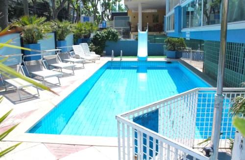 uma piscina azul com cadeiras e uma fonte em Hotel Diamond em Rimini