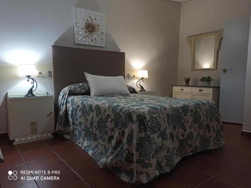 une chambre avec un lit, deux lampes et une horloge dans l'établissement Casa Rural: "la Encina", à Setenil de las Bodegas