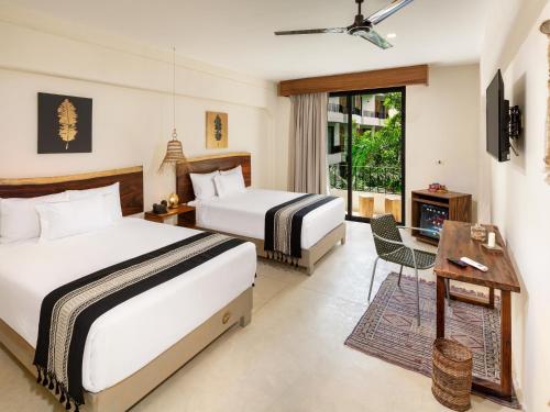 a hotel room with two beds and a television at Naala Tulum in Tulum