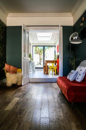 a living room with a red couch and a dining room at Regency Cottage in Brighton & Hove