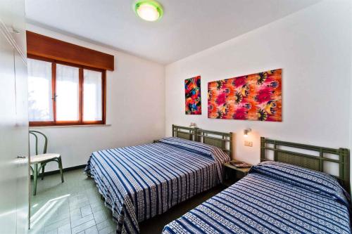 ビビオーネにあるApartments in Bibione 24392のベッドルーム1室(ベッド2台付)が備わります。壁には絵画が飾られています。