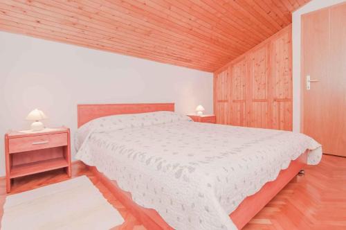 a bedroom with a white bed and a wooden ceiling at Apartments in Mali Losinj 14985B in Mali Lošinj