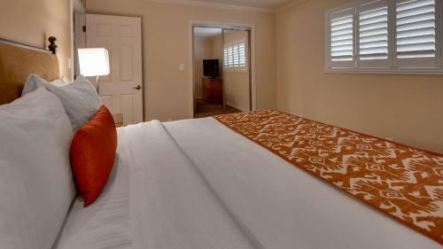 a bedroom with a large white bed with an orange pillow at Best Western Plus Arroyo Roble Hotel & Creekside Villas in Sedona