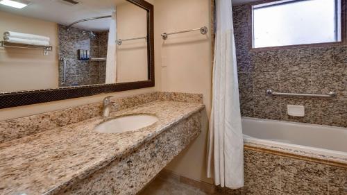 a bathroom with a sink and a tub and a mirror at Best Western Plus Arroyo Roble Hotel & Creekside Villas in Sedona