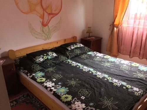 - un lit avec une couette noire et des fleurs dans l'établissement Holiday Home Balatonbereny 16, à Balatonberény