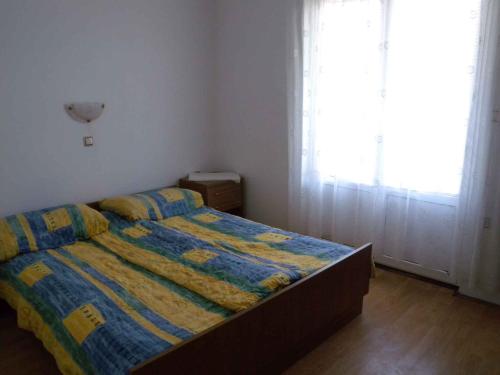 a bedroom with a bed with a blue and yellow comforter at Apartment Lopar 1 in Lopar
