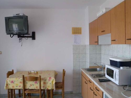 a kitchen with a table and a tv on the wall at Apartment Lopar 1 in Lopar