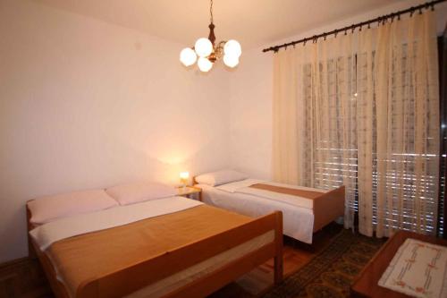 1 Schlafzimmer mit 2 Betten und einem Fenster mit einem Kronleuchter in der Unterkunft One-Bedroom Apartment Silo near Sea 1 in Šilo