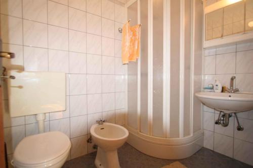 a white bathroom with a toilet and a sink at One-Bedroom Apartment Silo near Sea 6 in Šilo