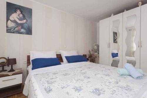 a white bedroom with a large bed with blue pillows at Studio in Crikvenica 5257 in Dramalj