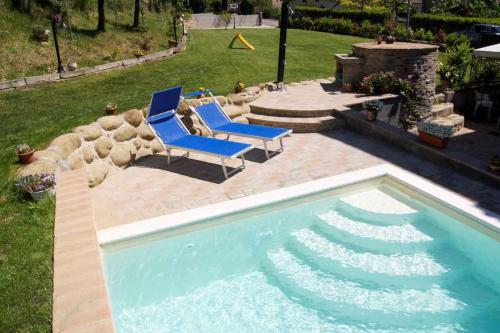 een zwembad met twee blauwe stoelen naast een tuin bij Apartment Umbertide 2 in Niccone