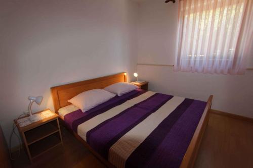 a bedroom with a bed with a purple and white striped blanket at Apartment Malinska, Krk 19 in Malinska