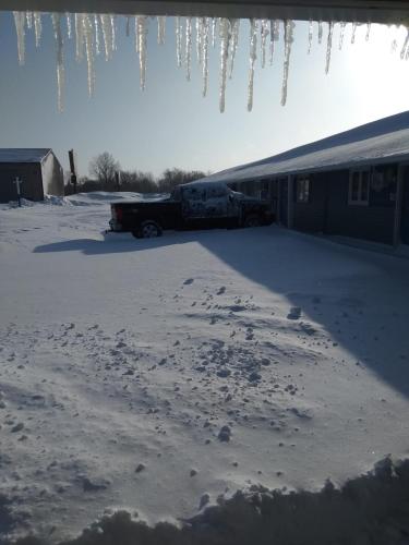 a truck parked in a snow covered yard with icicles at Burr Oak Motel in Algona