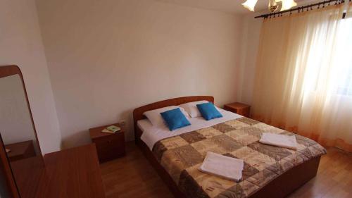 a bedroom with a bed with blue pillows and a window at Apartment in Malinska 12 in Sveti Vid-Miholjice