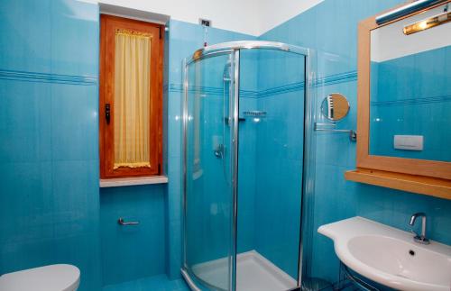 baño azul con ducha y lavamanos en Marc Hotel, en Vieste