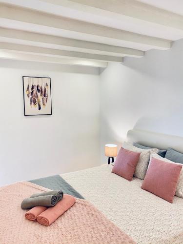 a white bedroom with a large bed with pink pillows at Porto Wine Loft Duplex with swimming pool in Vila Nova de Gaia