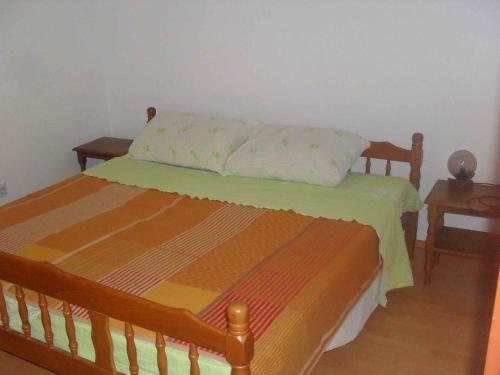 a bedroom with a wooden bed with a pillow on it at Apartment Lopar 9 in Lopar