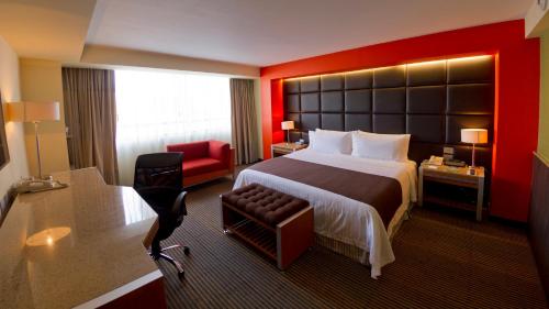a hotel room with a large bed and a red wall at Holiday Inn Mexico City-Plaza Universidad by IHG in Mexico City