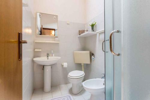 een witte badkamer met een toilet en een wastafel bij Apartment Privlaka 12 in Privlaka