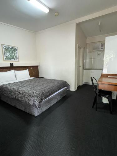 Allambie Motel في Condobolin: غرفة نوم بسرير وطاولة ومكتب