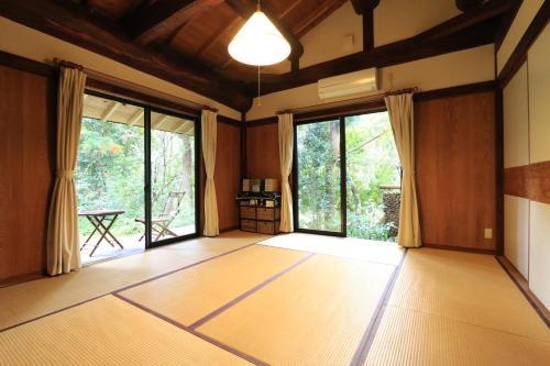 ein leeres Zimmer mit Holzböden und großen Fenstern in der Unterkunft Wa no Cottage Sen-no-ie in Yakushima