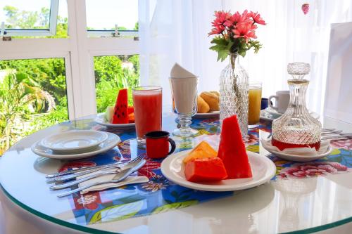 uma mesa com pratos de frutas e um vaso de flores em Pousada Pomar De Manguinhos em Manguinhos