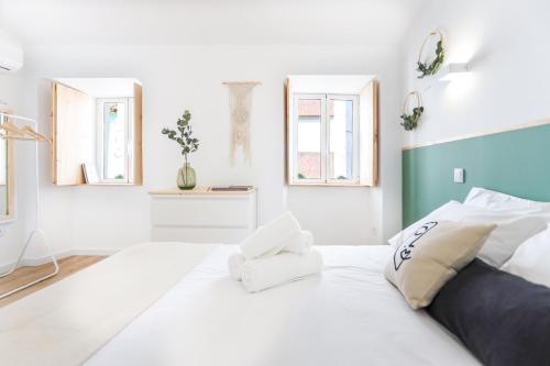 um quarto branco com uma cama grande e 2 janelas em Casa da Praça em Brangança