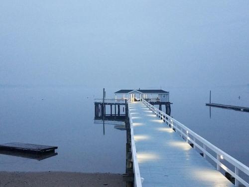 a dock with a house on the water at Fathoms Hotel & Marina in Port Washington