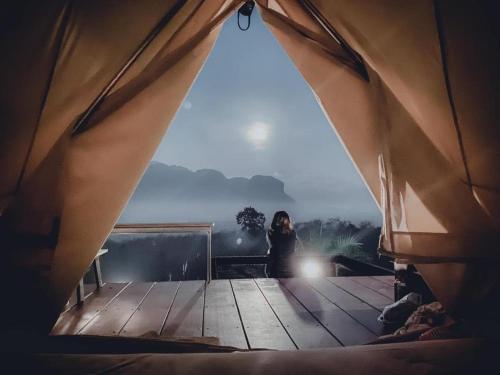 a woman sitting inside of a tent with a view at Por Sampao Camp&Resort in Ban Pha Saeng Lang