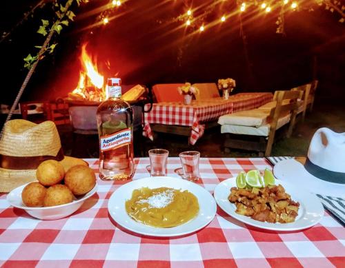 una mesa con platos de comida y una botella de alcohol en Casa Roja Parche Campestre - Hospedaje Guatapé, en Guatapé