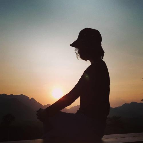 a woman sitting on a ledge looking at the sunset at Por Sampao Camp&Resort in Ban Pha Saeng Lang