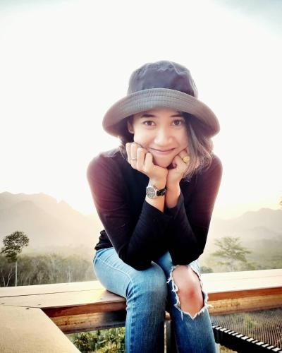 a girl sitting on a bench wearing a hat at Por Sampao Camp&Resort in Ban Pha Saeng Lang
