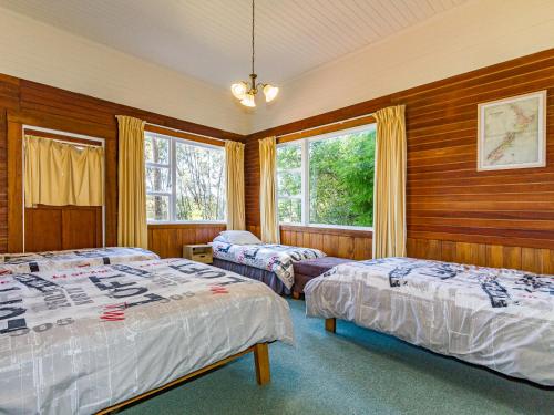 two beds in a room with wooden walls and windows at The Station - Ohakune Holiday Home in Ohakune