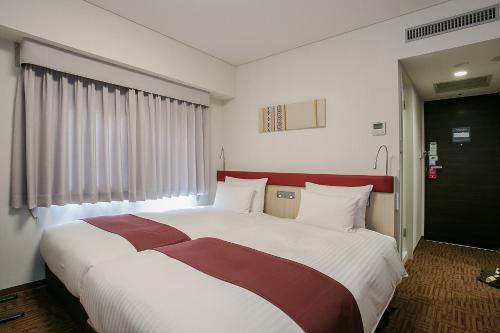 a bedroom with a large bed with white and red sheets at Mars Garden Hotel Hakata in Fukuoka