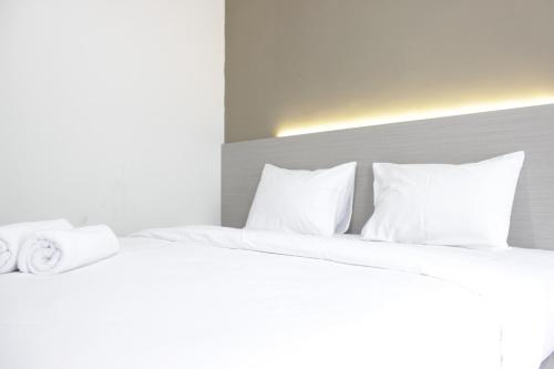 a bedroom with two beds with white sheets and pillows at Comfy Studio Apartment at Harvard Jatinangor near UNPAD By Travelio in Sayang