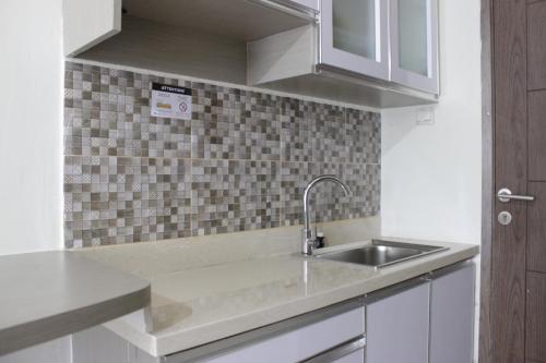 a kitchen with a sink and a tile wall at Comfy Studio Apartment at Harvard Jatinangor near UNPAD By Travelio in Sayang