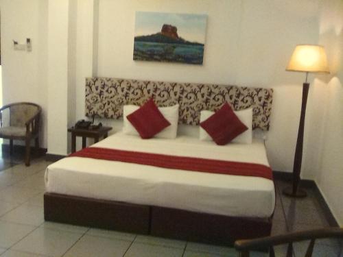 a hotel room with a large bed with red pillows at Heaven Seven Kandy in Kandy