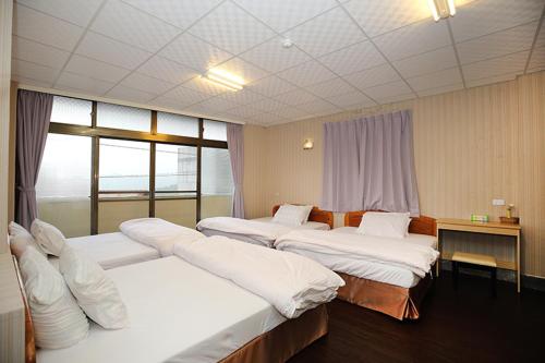 pokój hotelowy z 3 łóżkami i oknem w obiekcie Zhongshan Hostel w mieście Fenchihu