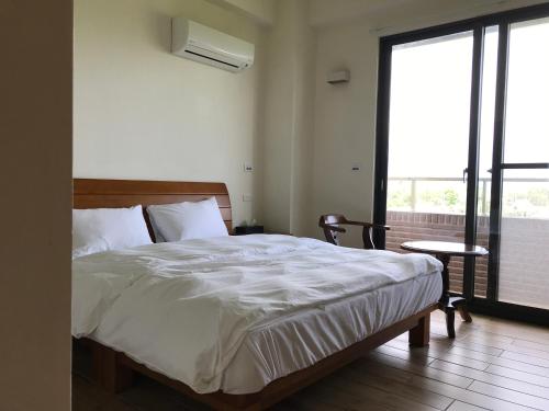 1 dormitorio con 1 cama grande con sábanas blancas en Furutasou B&B, en Fenglin